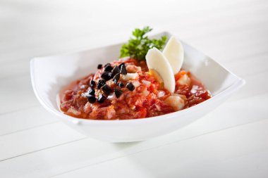 Siyah zeytinli domates ve yumurta salatası ve beyaz kasede maydanoz.