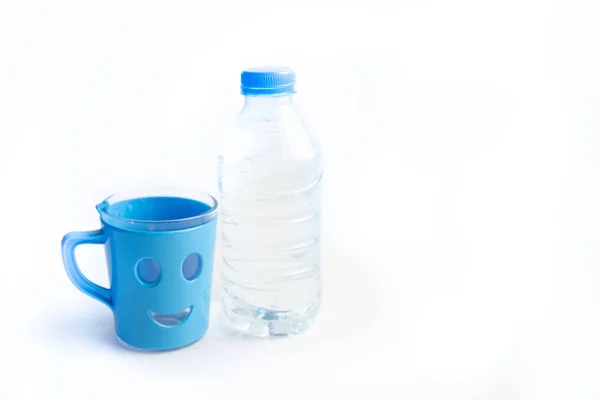 Μπουκαλάκι πλαστικό με καθαρό μεταλλικό πόσιμο νερό και γυάλινο κύπελλο με χαμόγελο. Κοντινό πλάνο. — Φωτογραφία Αρχείου