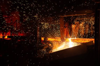 Meşale kesiminde sıcak kırmızı çelik kirişler. Demirci ve metalurji endüstrisinin arka planı.