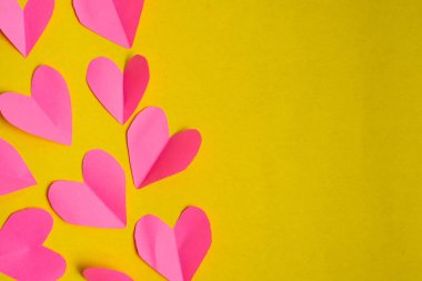 Sarı arka planda kırmızı kağıt kalpler. Sevgililer Günü konsepti.