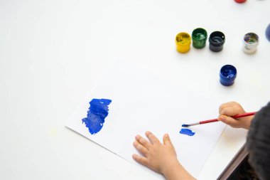 Küçük çocuk kağıda resim çizer. Şirin Çocuk oturuyor ve resim yapıyor. Evde kal..