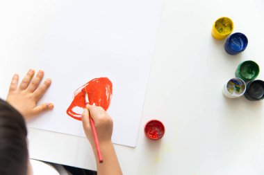 Küçük çocuk kağıda resim çizer. Şirin Çocuk oturuyor ve resim yapıyor. Evde kal..