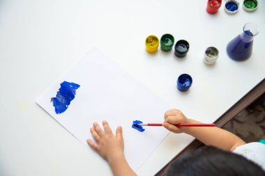 Küçük çocuk kağıda resim çizer. Şirin Çocuk oturuyor ve resim yapıyor. Evde kal..