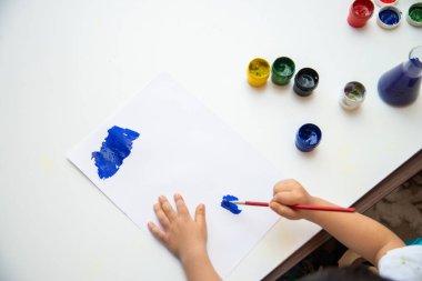 Küçük çocuk kağıda resim çizer. Şirin Çocuk oturuyor ve resim yapıyor. Evde kal..