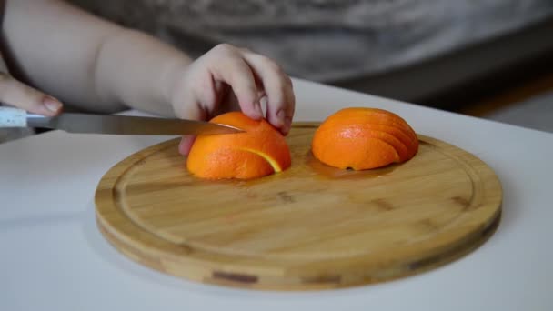 木製ボード上の手スライスオレンジ 主婦の女性は 自宅でサラダや台所でジュースのためのまな板の上に新鮮なオレンジの果物をスライス — ストック動画