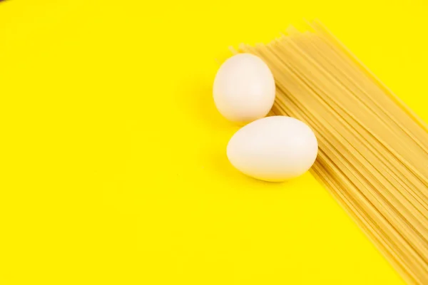 Food stock for quarantine isolation period on yellow background. Egg and spaghetti. Food delivery, Donation. Copyspace