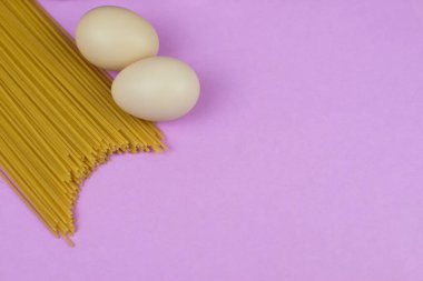 Mor arka planda karantina süresi için yiyecek stoku. Yumurta ve spagetti. Yemek teslimatı, bağış. Kopyalama alanı
