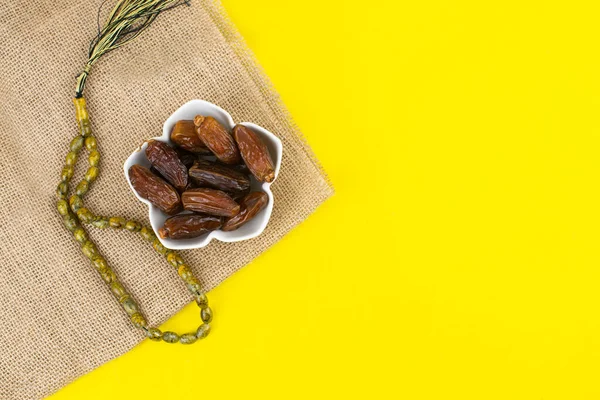 Festival Ramadán Kareem. Primer plano de dátiles secos fruta en tazón con rosario sobre fondo amarillo. Copiar espacio . — Foto de Stock