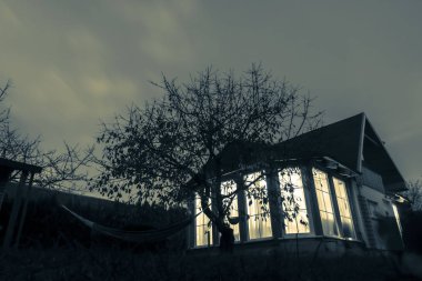 Aile evi, sonbahar akşamı, tek renk ağaç hizasında.