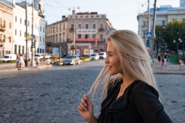 Chernivtsi, Ukrayna, 25.08.2019: Siyah elbiseli mutlu sarışın kadın hafta sonu boyunca yabancı bir şehirde gezintiye çıktı