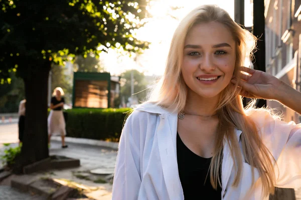Czerniowce, Ukraina, 25.08.2019: Szczęśliwa blondynka w białej koszuli, zachód słońca na tle — Zdjęcie stockowe