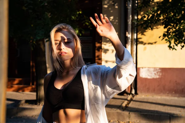 Menina loira sexy em camisa branca cobre seu rosto com a mão dos raios de sol — Fotografia de Stock