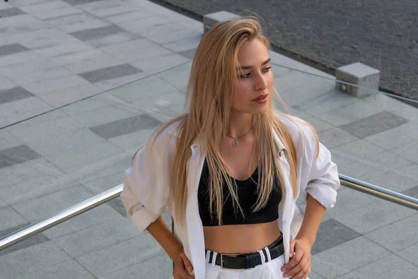 Stylish blonde woman with natural make up dressed in white shirt holds her hands on her waist — Stock Photo, Image