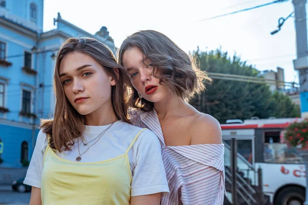 Retrato de dos chicas morenas sensuales en ropa casual con labios rojos de pie juntos entre el centro de la ciudad vieja —  Fotos de Stock