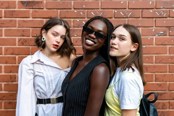 Glad smide multietniska flickor i casual kläder isolerade över röd tegelvägg — Stockfoto