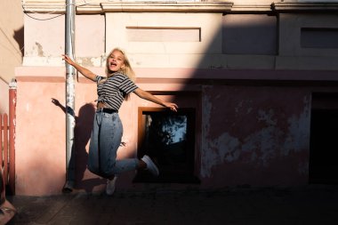 Mutlu, heyecanlı, gevşek saçlı, sıradan elbiseli genç kız eski şehrin sokaklarında zıplıyor.
