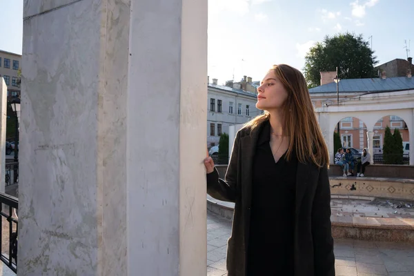 Menina orgulhosa atraente com cabelo solto vestido de manto preto fica entre a praça da cidade velha — Fotografia de Stock