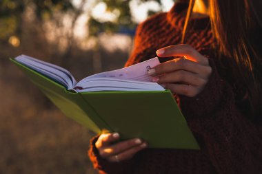 Kapalı portre, kırmızı kazaklı genç kız elinde yeşil defter tutuyor.
