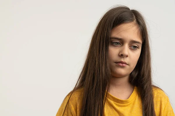 Retrato de la cintura hacia arriba de la chica morena triste, triste y molesta con el pelo suelto, vestida con una camiseta amarilla aislada sobre fondo blanco — Foto de Stock