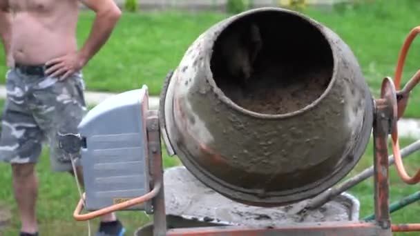 Arbeiter schüttet Sand mit Schaufel in Betonmischer — Stockvideo