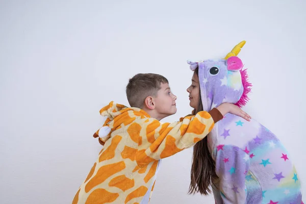 Sidovy porträtt av glada barn, pojke och flicka, bror i giraff pyjamas lägga händerna på systrar axlar, lekfulla barn tittar på varandra, isolerade över vit bakgrund — Stockfoto