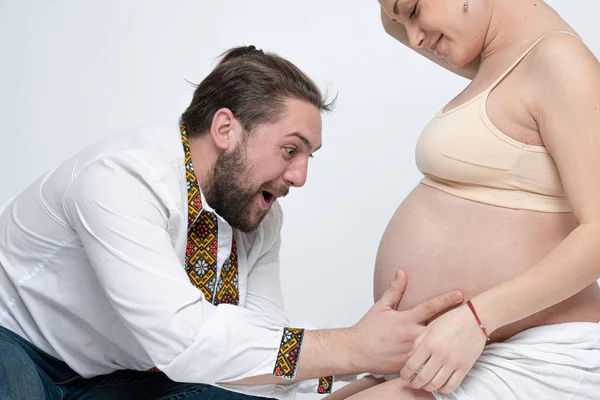 Felice barbuto giovane uomo toccare pancia della sua bella moglie. Coppia incinta di marito e moglie sente amore. Fondo bianco — Foto Stock