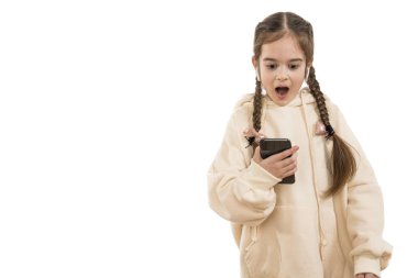 Beyaz arka planda izole edilmiş telefon ve kablosuz kulaklıklar kullanarak bej kapüşonlu örgülü saçları olan genç bir kız.