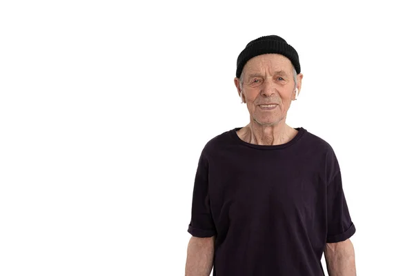 Homem velho feliz em t-shirt preta e chapéu, elegante sênior em fones de ouvido sem fio brancos olhando para a câmera isolada sobre espaço de cópia de fundo branco para o seu texto — Fotografia de Stock