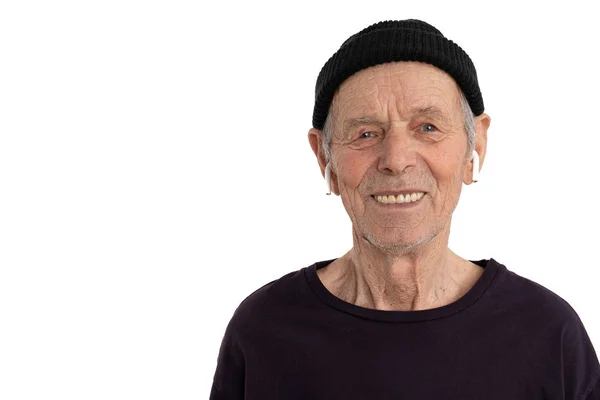 Старый счастливый человек в черной футболке и шляпе, стильный старшеклассник в белых воздушных стручках, смотрящий на камеру, изолированную на белом фоне копирайта для вашего текста — стоковое фото