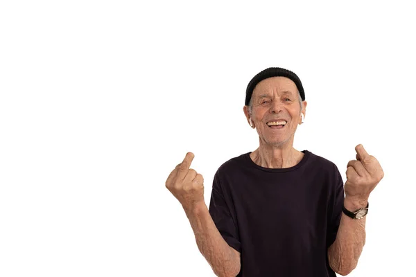 Happy smiling old man in black hat, white airpods and t-shirt, stylish senior showing middle finger with a missing phalanx doing fuck you bad expression, provocation and rude attitude, isolated over — Stockfoto