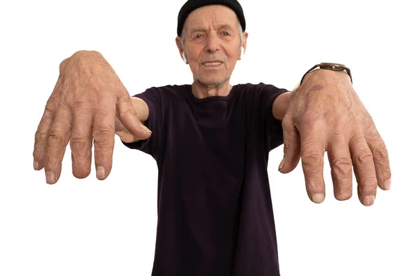 Confident old man in black t-shirt and hat, stylish senior in white wireless headphones showes his hands with a missing middle finger phalanx, isolated over white background — Stock Photo, Image