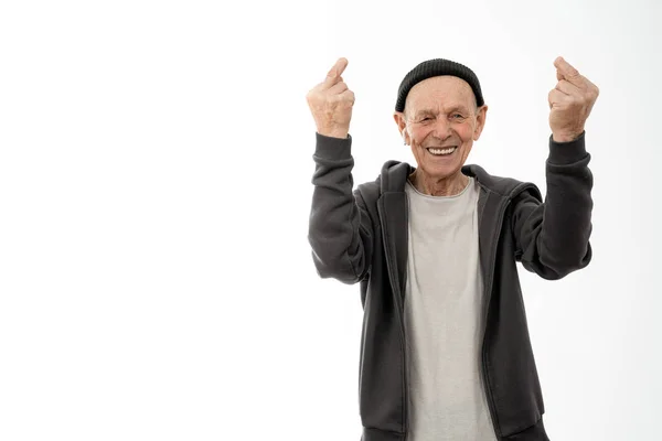 Happy smiling old man in black hat , white headphones and hoodie, stylish senior showing middle finger with a missing phalanx doing fuck you bad expression, provocation and rude attitude, isolated — Stock Photo, Image