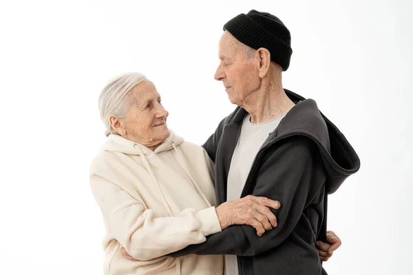 Atractiva pareja de ancianos encantadores en sudaderas con capucha bailando aislados sobre fondo blanco — Foto de Stock