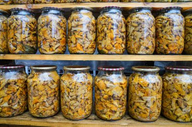 Tasty brown pickled mushrooms in a glass jar close up, homemade pickles