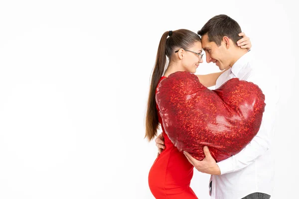 Hermosa pareja romántica aislada sobre fondo blanco. Atractiva joven mujer y hombre guapo están abrazando con el corazón rojo en las manos. Feliz día de San Valentín Copyspace para su texto . — Foto de Stock