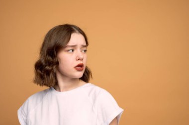 Portakal rengi arka planda izole edilmiş fotokopi alanına bakan düşünceli bir kızın portresi