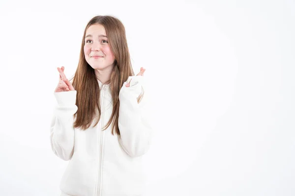 Pleased cheerful brunette woman puts all efforts in wishing good luck, crosses fingers, has faith for better, dressed in oversized hoodie, isolated over pink background — Stockfoto