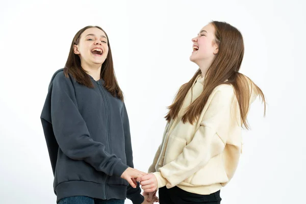 Happy girls in hoodies holding hands together and laughing isolated over white background — Stock fotografie