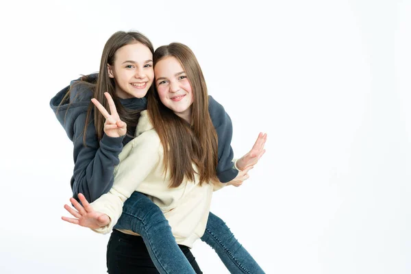 Glada unga vänner klädda i hoodies njuter av tid tillsammans, brunett kvinnliga visar seger tecken och tittar på kameran, isolerade över vit bakgrund — Stockfoto