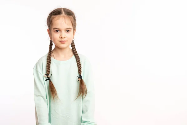 Confident child girl with pigtails dressed in green shirt looking at the camera isolate over white background — Stockfoto