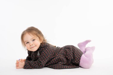 Close up portrait of the charming, pretty kid in dress, girl with red hair liying on the floor and looking at the camera