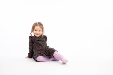 Funny redhead girl in purple tights sitting on the floor and looking at the camera isolated over white background