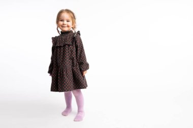 Playful redhead little girl in red pea dress looking at the camera isolated over white background