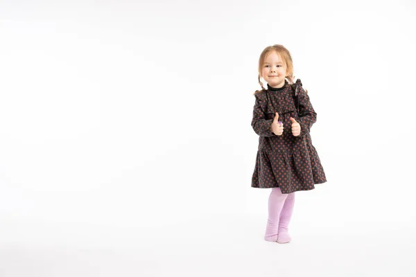 Full lenght portrait of the pretty redhead girl in dress holding thumbs up isolated on white background — Stockfoto