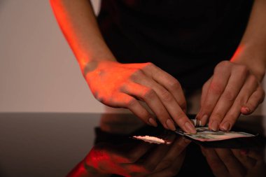 Genç kızların elleri dolar banknotunun üzerinde, kokain çizgisi siyah masanın üzerinde.