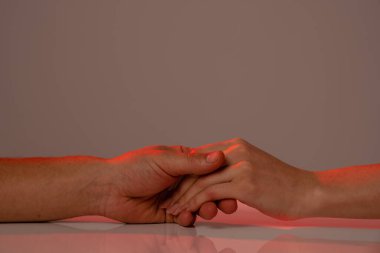 Beyaz bir masada el ele tutuşan bir kadın ve bir adama yaklaş. Gri arka planda izole edilmiş.