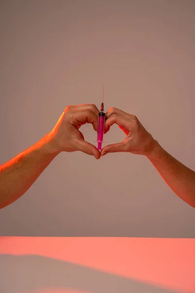 Herzschild mit rosa Spritze isoliert über grauem Wandhintergrund — Stockfoto