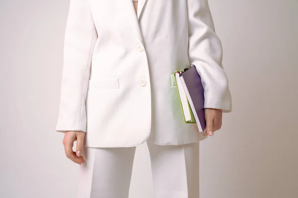 Обрізана фотографія, жінка в білому блістері тримає блокноти в руці ізольовані на сірому фоні — стокове фото