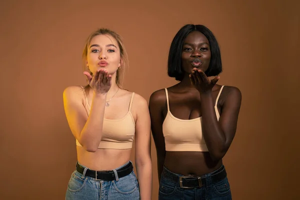 Photo de deux dames coquettes internationales dans l'envoi de beaux gars air kiss porter tenue décontractée isolé sur fond orange foncé — Photo