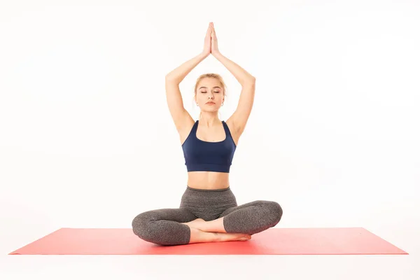 Sağlıklı bir yaşam tarzı ve yoga - jimnastik kostümlü bir yoga eğitmeni olan çekici bir kadın beyaz arka planda izole edilmiş ana asmalardan birini oluşturur. — Stok fotoğraf